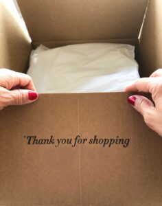 woman opening a box with thank you for shopping written on it as a way of saying thank you for supporting my small business
