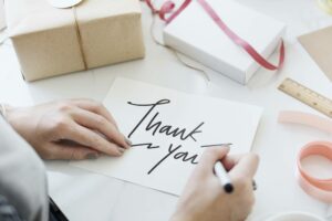 woman writing thank you on a note to say thank you for your purchase
